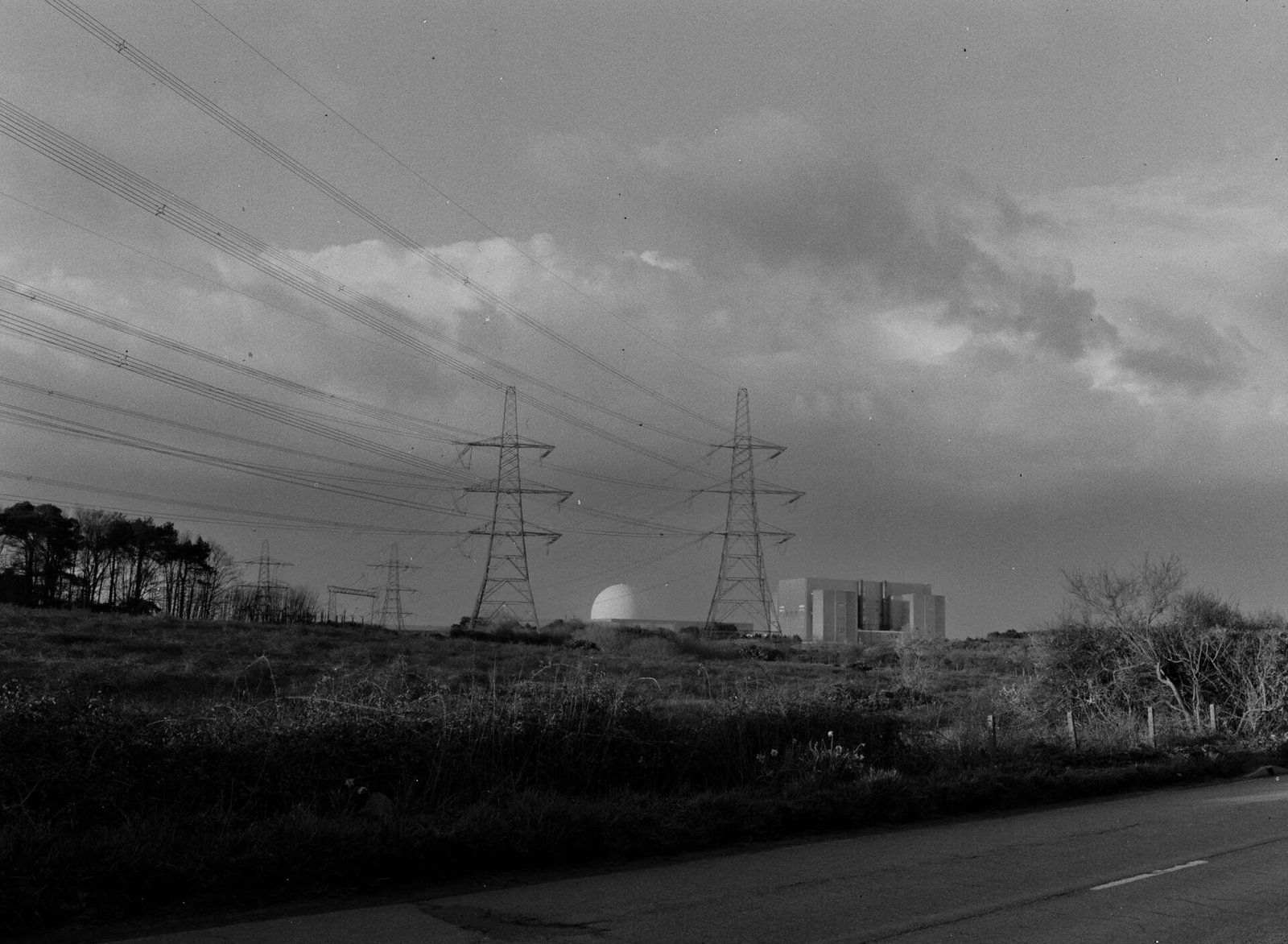 Sizewell B nuclear power station and its rectangular turbine hall framed between electricity pylons, with power lines crossing the sky