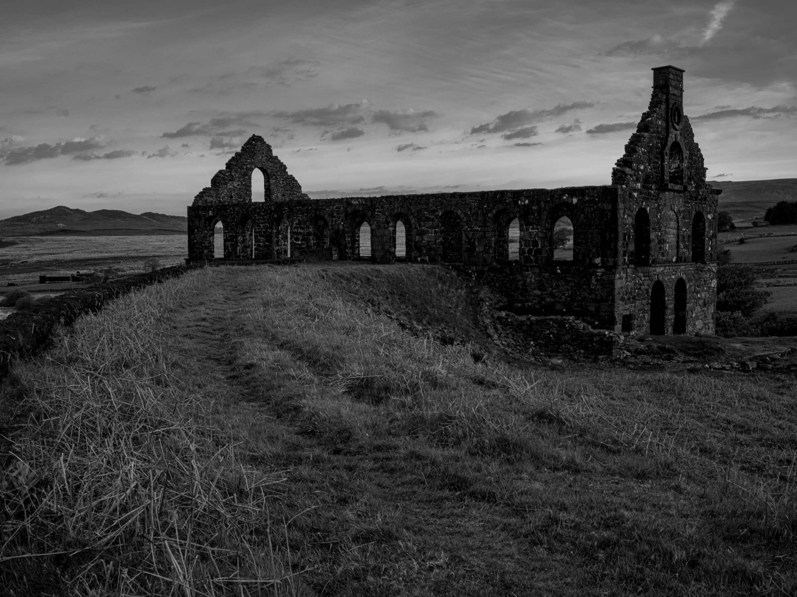 The ruined Ynys y Pandy slate mill at dawn, built to serve Gorseddau Quarry, its gable end and arched windows silhouetted against the sky.