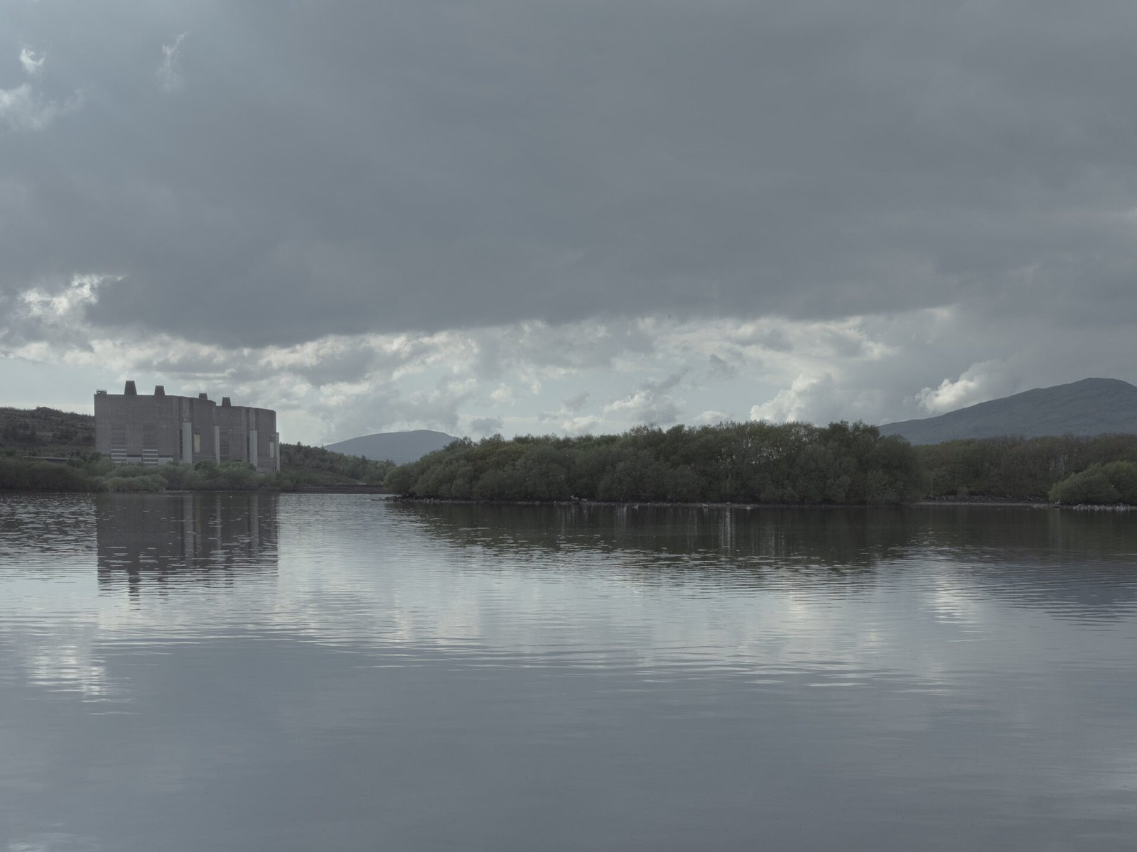 Trawsfynydd nuclear reactor reflected in the still water of Llyn Trawsfynydd with mountain backdrop, Eryri
