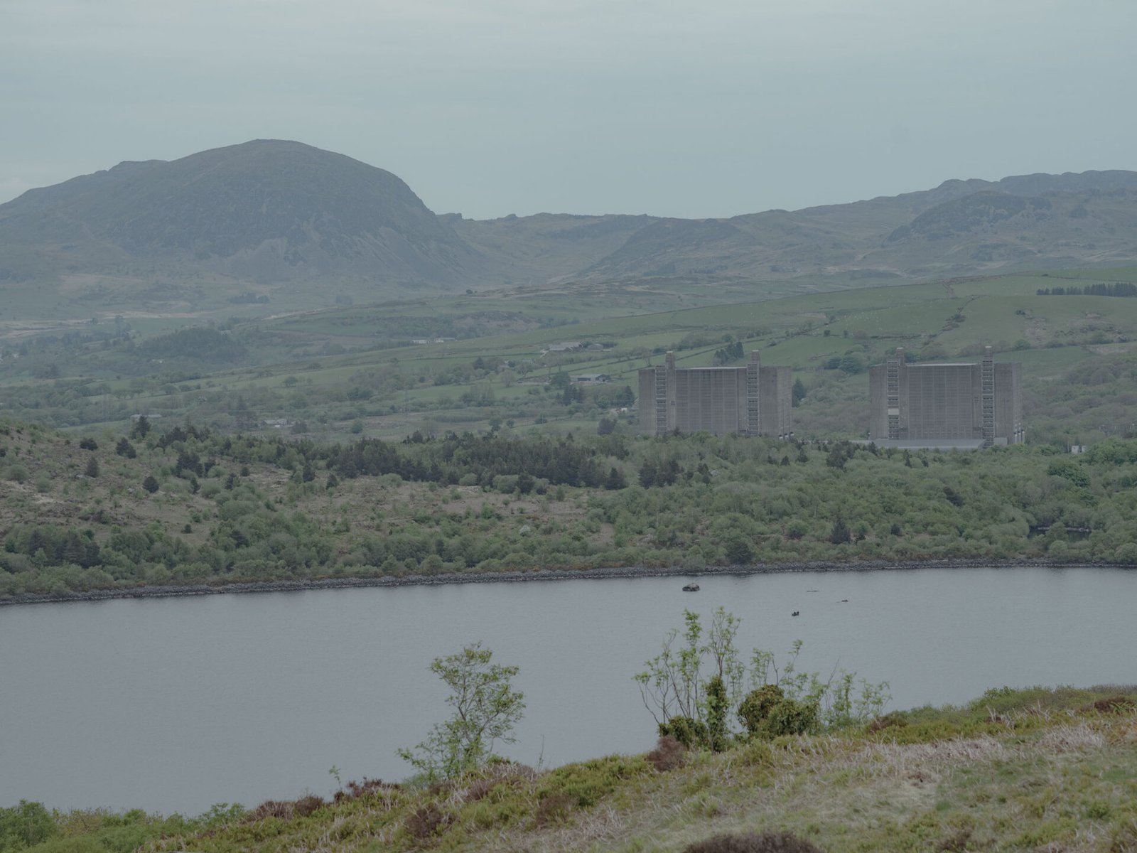 Trawsfynydd nuclear reactors seen from Cwm Moch across the Llyn, dwarfed by the surrounding mountains of Eryri